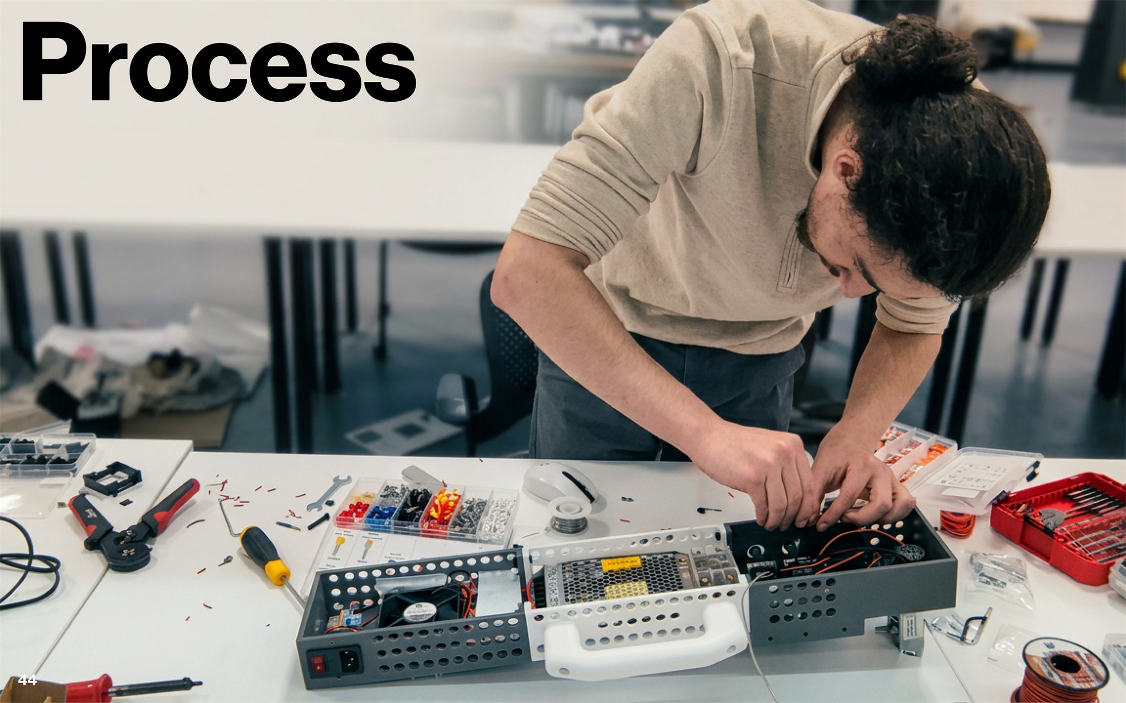 Hands-on fabrication process with electronics, fasteners, enclosure components, and control hardware on the workbench.